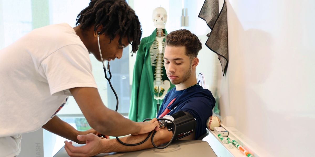 two students practicing with blood pressure cuff