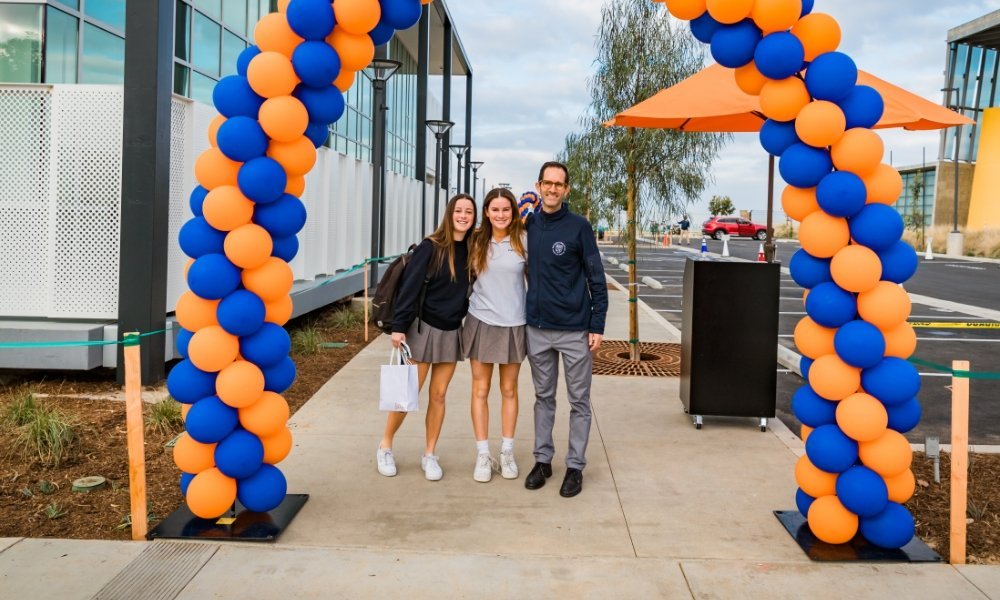 students posing under blue and orange balloon arch
