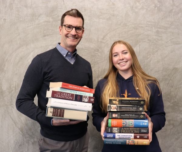 Pacifica student and teacher holding stacks of books