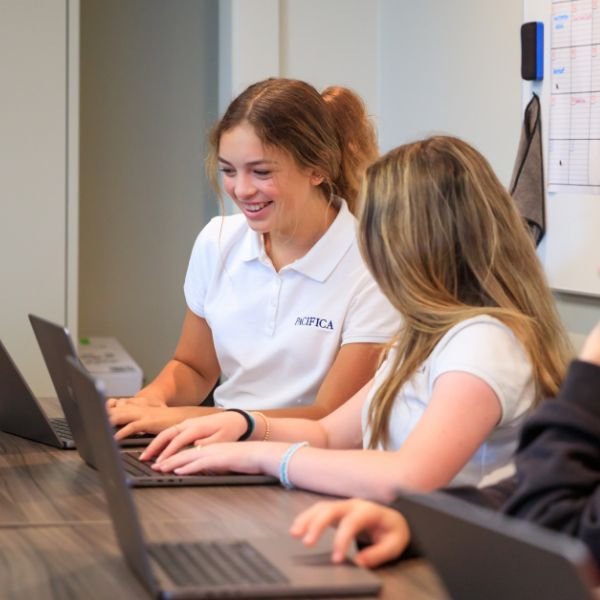 two Pacifica students working on laptops