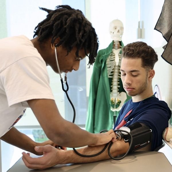 two Pacifica students practicing using a blood pressure cuff
